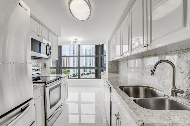 kitchen featuring white cabinetry, appliances with stainless steel finishes, backsplash, and a sink