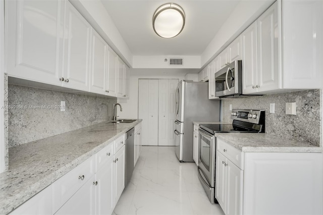 kitchen featuring white cabinets, sink, decorative backsplash, light stone countertops, and appliances with stainless steel finishes