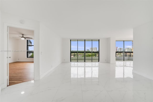 empty room with plenty of natural light, ceiling fan, and light hardwood / wood-style flooring