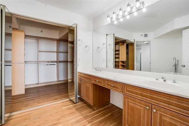 bathroom with double vanity, visible vents, a sink, and wood finished floors