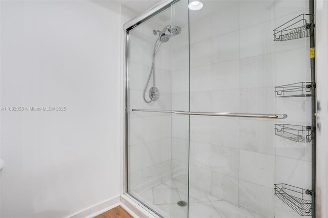 bathroom with hardwood / wood-style flooring and a shower with shower door