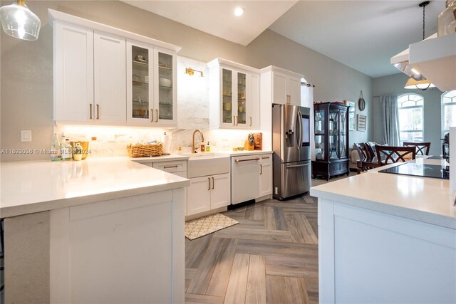 kitchen with stainless steel appliances, dark parquet floors, hanging light fixtures, sink, and white cabinetry