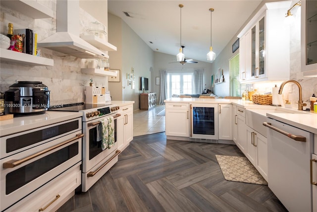 kitchen with appliances with stainless steel finishes, exhaust hood, hanging light fixtures, white cabinets, and beverage cooler