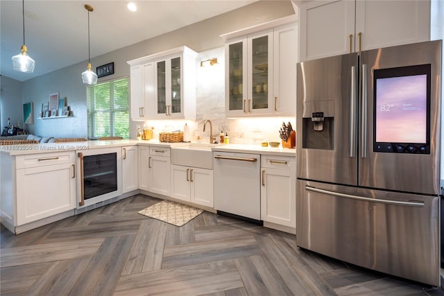 kitchen with appliances with stainless steel finishes, decorative light fixtures, sink, white cabinets, and beverage cooler