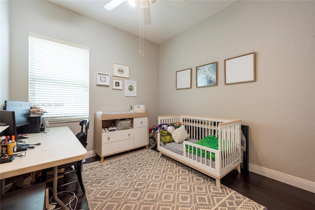 bedroom featuring hardwood / wood-style flooring, ceiling fan, and a nursery area