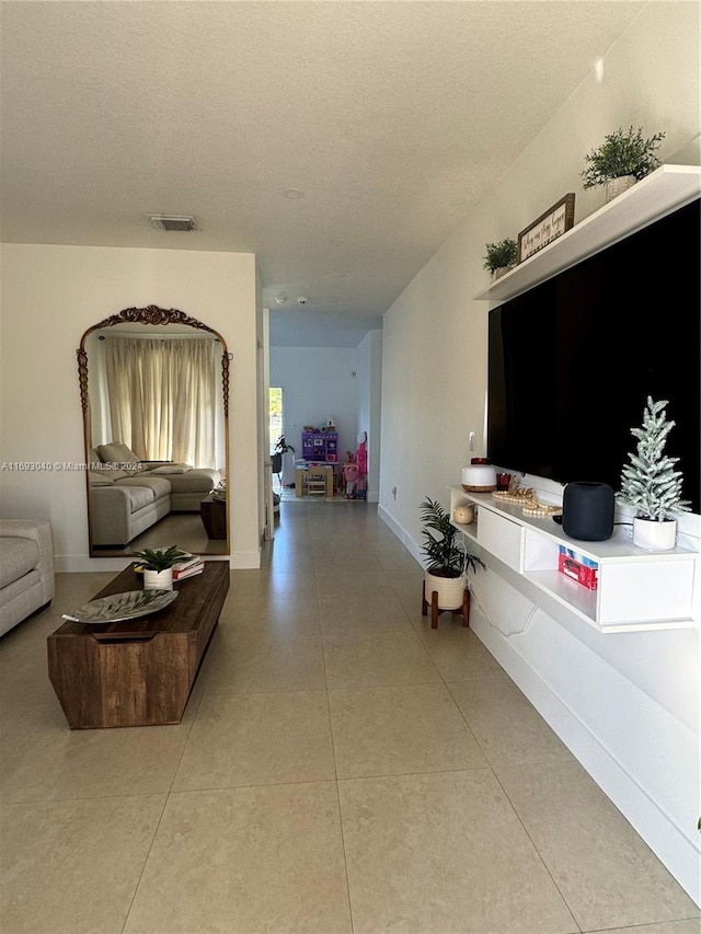 hallway with a textured ceiling and tile patterned floors