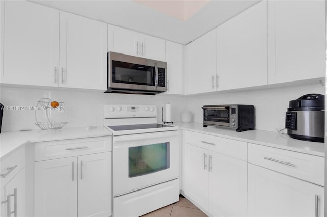 kitchen with white cabinets, light tile patterned flooring, and electric range