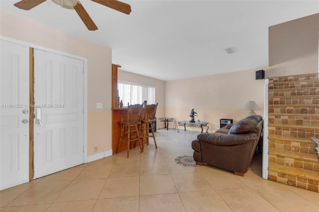 living room featuring light tile patterned flooring, ceiling fan, and indoor bar