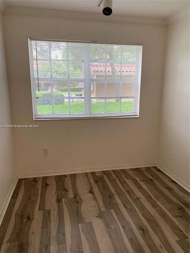 empty room featuring ornamental molding and dark hardwood / wood-style flooring