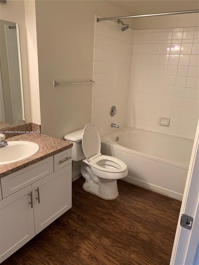 full bathroom featuring vanity, tiled shower / bath, hardwood / wood-style floors, and toilet