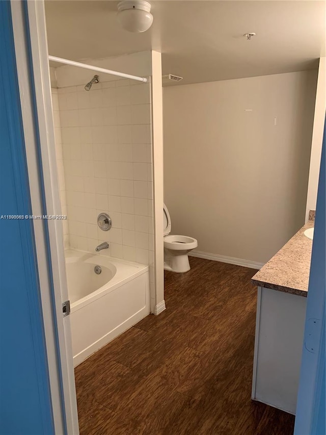 full bathroom featuring tiled shower / bath combo, vanity, hardwood / wood-style floors, and toilet