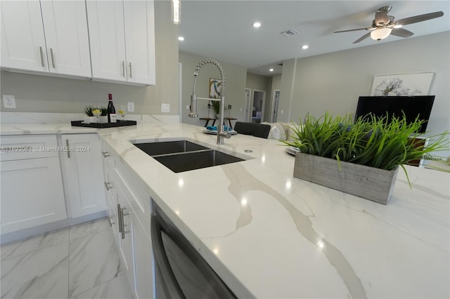 kitchen with ceiling fan, dishwasher, sink, light stone counters, and white cabinets