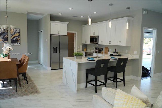 kitchen featuring white cabinetry, stainless steel appliances, a kitchen breakfast bar, kitchen peninsula, and pendant lighting