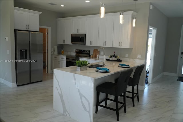 kitchen with a kitchen bar, white cabinetry, pendant lighting, and stainless steel appliances