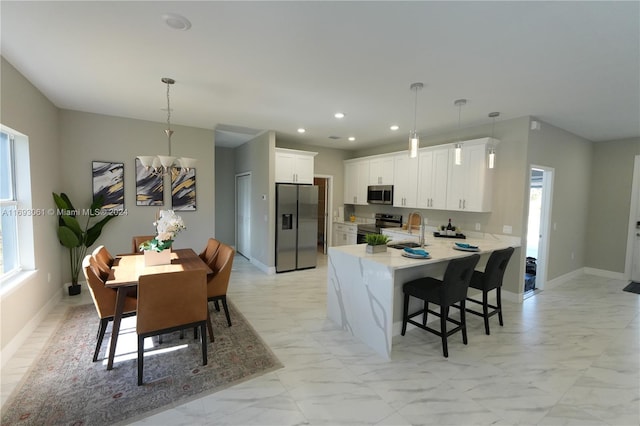 kitchen featuring sink, white cabinets, decorative light fixtures, and appliances with stainless steel finishes