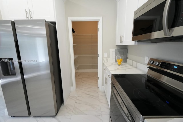 kitchen with light stone countertops, white cabinetry, and stainless steel appliances