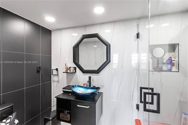 bathroom with vanity, an enclosed shower, and tile walls