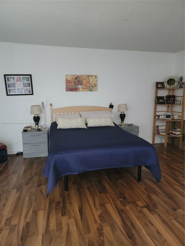 bedroom with dark wood-type flooring and a textured ceiling