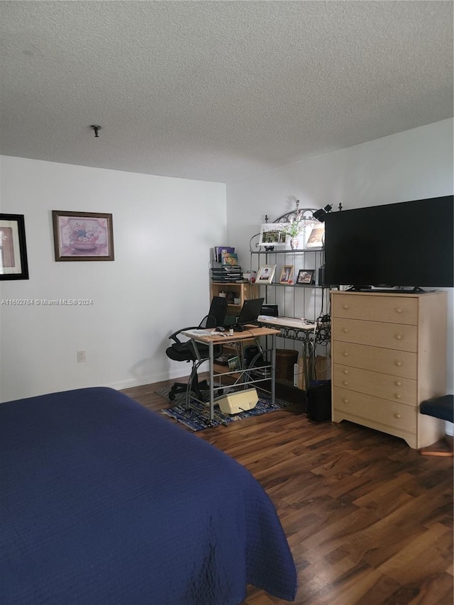 bedroom with dark hardwood / wood-style flooring and a textured ceiling