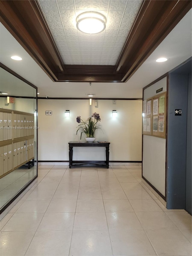 hall with a mail area, light tile patterned floors, and a raised ceiling