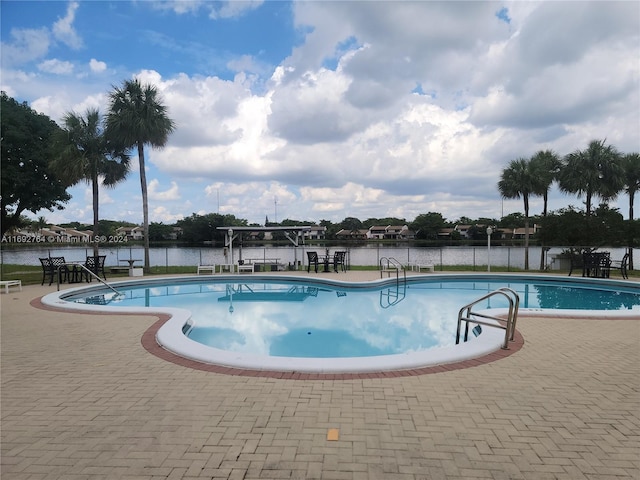 view of swimming pool with a water view and a patio