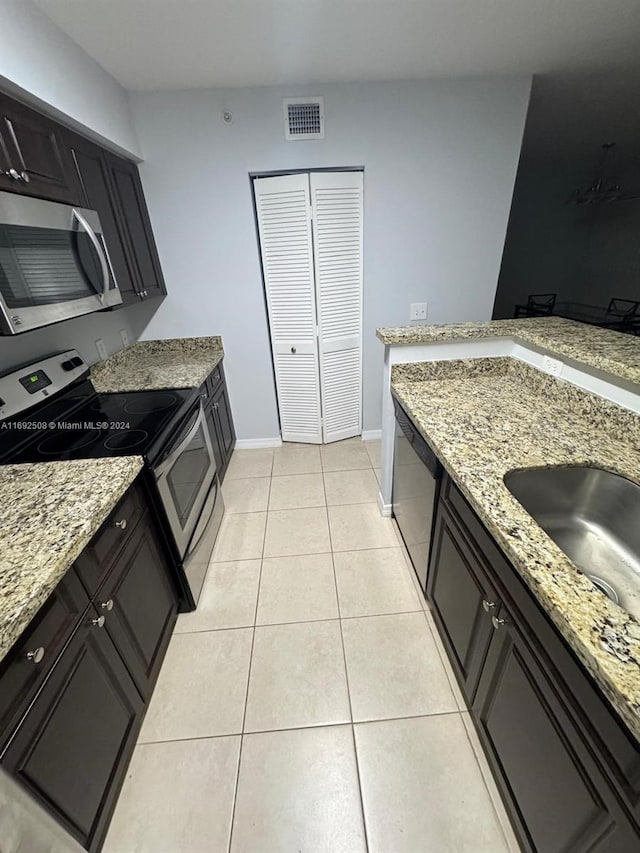 kitchen featuring sink, light stone counters, light tile patterned floors, and stainless steel appliances