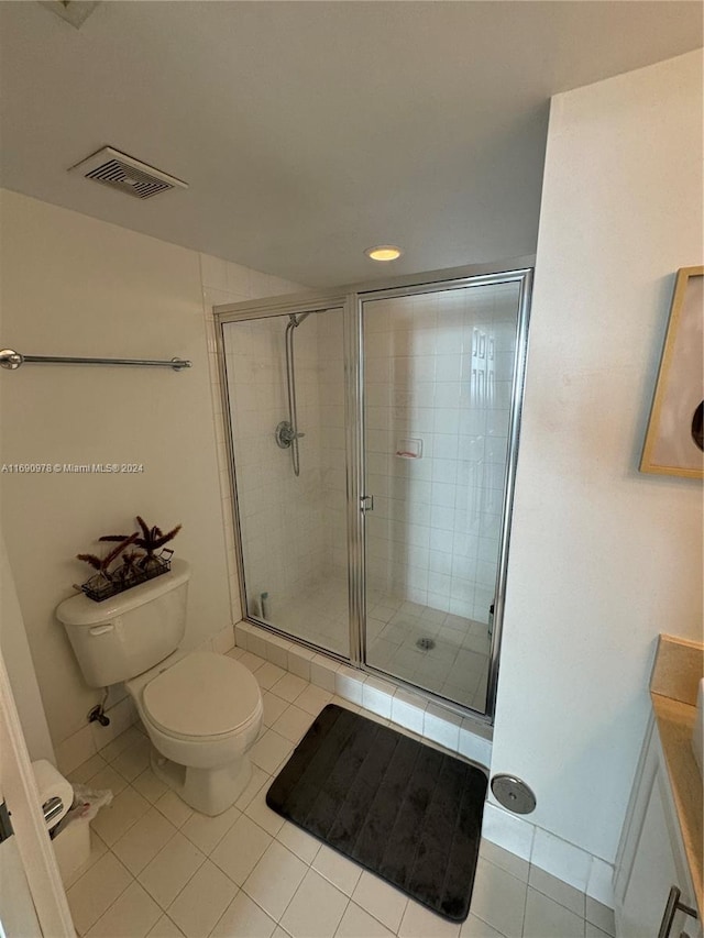 bathroom featuring toilet, vanity, an enclosed shower, and tile patterned floors