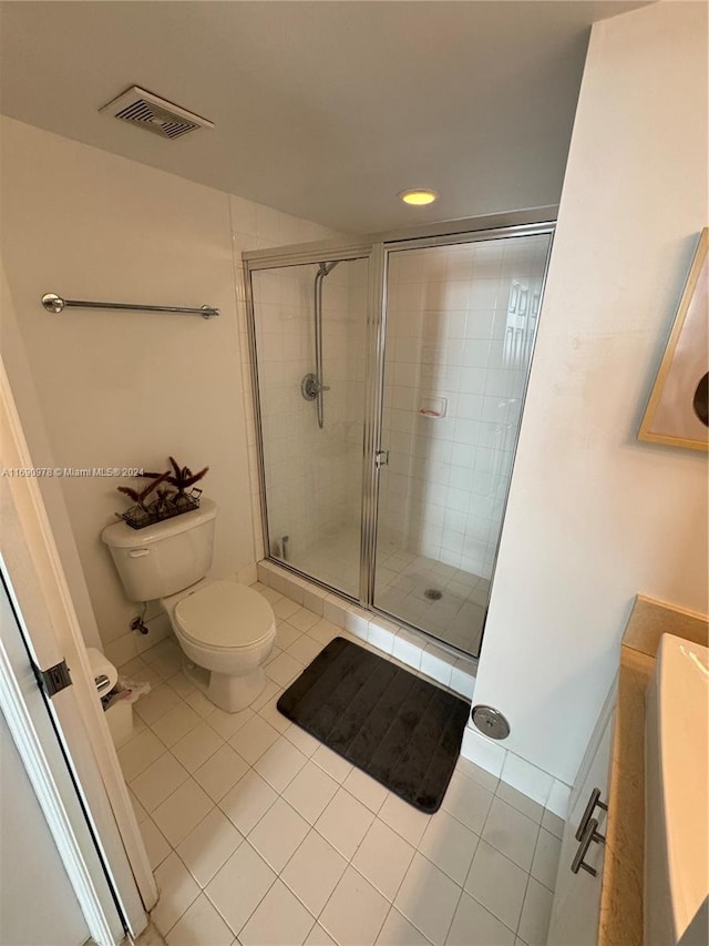 bathroom with a shower with shower door, tile patterned flooring, and toilet