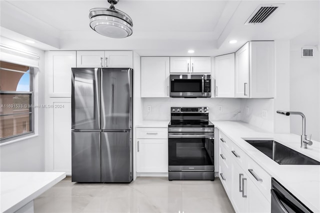 kitchen with white cabinetry, sink, light stone counters, and appliances with stainless steel finishes