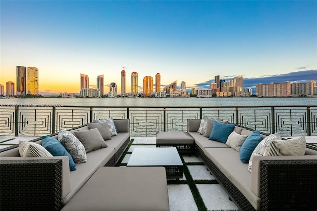 patio terrace at dusk with a balcony, a water view, and an outdoor hangout area