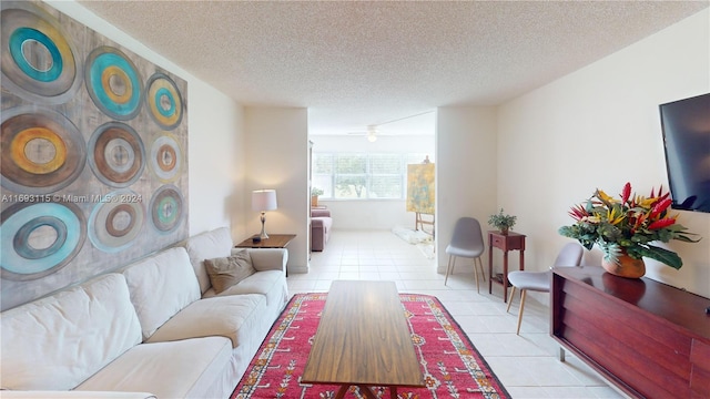 living room with ceiling fan, light tile patterned flooring, and a textured ceiling