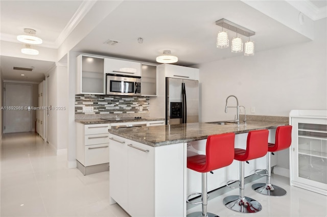 kitchen with appliances with stainless steel finishes, tasteful backsplash, sink, decorative light fixtures, and white cabinetry