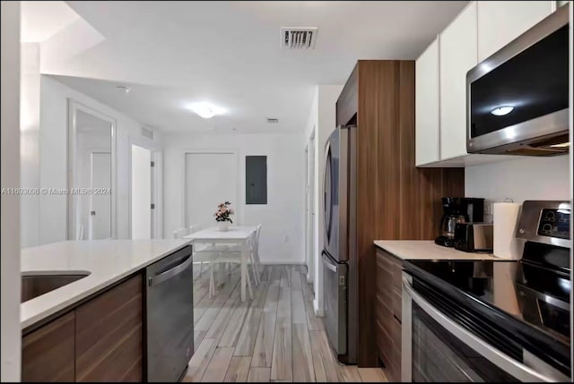 kitchen featuring light wood-type flooring, white cabinetry, and stainless steel appliances