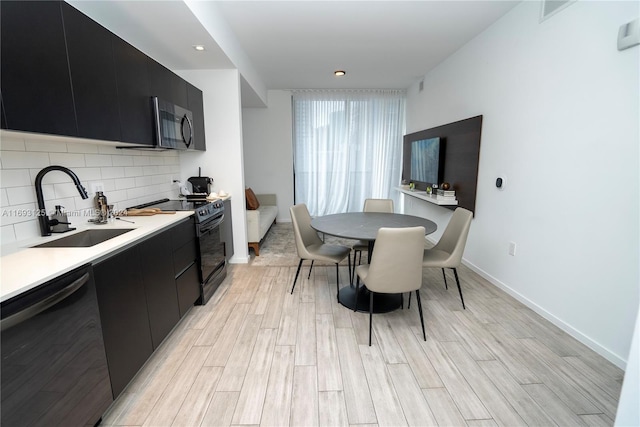 kitchen with backsplash, appliances with stainless steel finishes, sink, and light hardwood / wood-style flooring