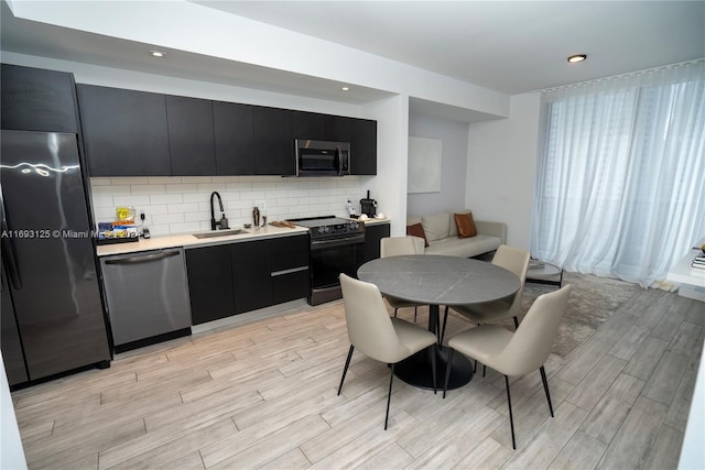 398 NE 5th St Unit 1617, Miami, FL 33132 - kitchen featuring appliances with stainless steel finishes, dark cabinets, a sink, light wood-type flooring, and recessed lighting