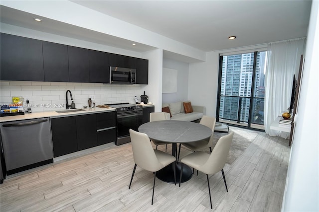 kitchen with light hardwood / wood-style floors, stainless steel appliances, sink, and decorative backsplash