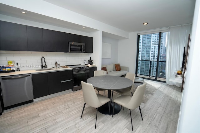 398 NE 5th St Unit 1617, Miami, FL 33132 - kitchen featuring stainless steel appliances, dark cabinets, a sink, light wood-style floors, and a wall of windows