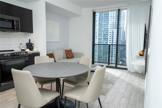 dining area with expansive windows and light hardwood / wood-style flooring