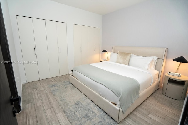 bedroom featuring multiple closets and light hardwood / wood-style flooring