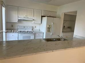 kitchen featuring white appliances, sink, and light stone counters