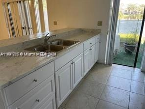 kitchen featuring white cabinetry, sink, and light tile patterned floors