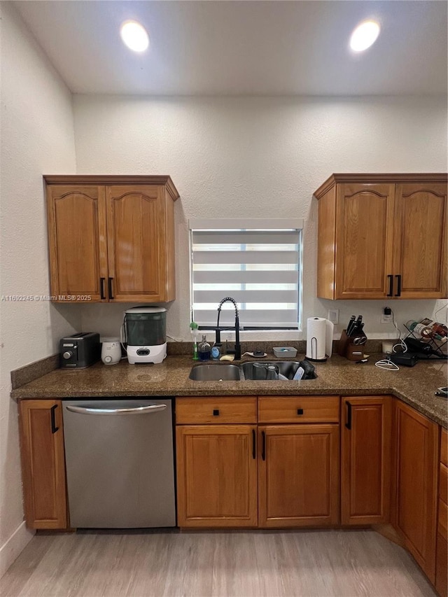 kitchen with sink, light wood-type flooring, dark stone counters, and dishwasher