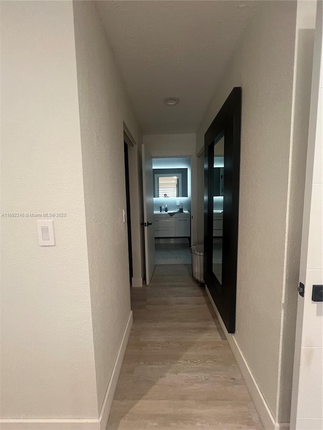 hallway with sink and light wood-type flooring