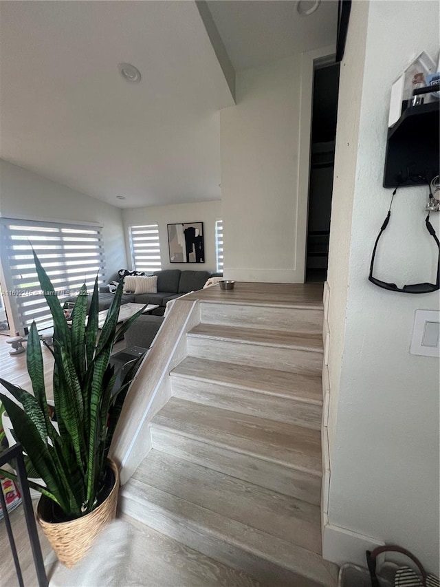 stairway with hardwood / wood-style floors and lofted ceiling