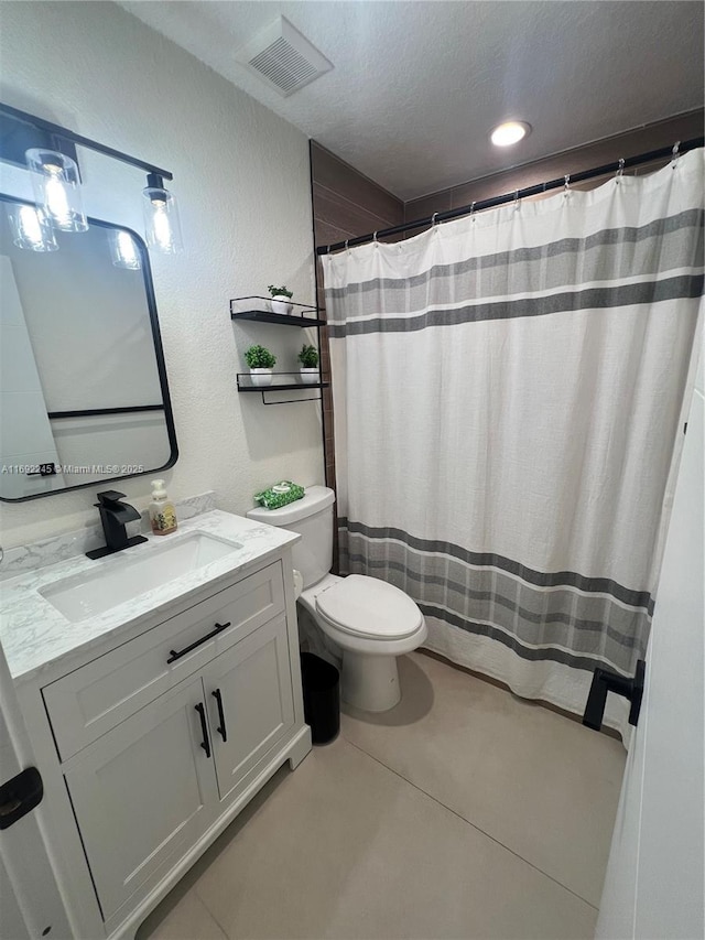 bathroom with tile patterned floors, a textured ceiling, toilet, and vanity