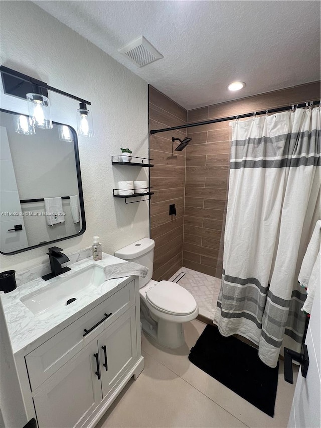 bathroom with tile patterned flooring, toilet, a textured ceiling, walk in shower, and vanity