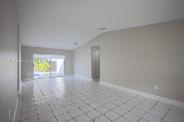 tiled empty room featuring vaulted ceiling