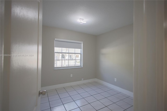 empty room with light tile patterned floors and a textured ceiling