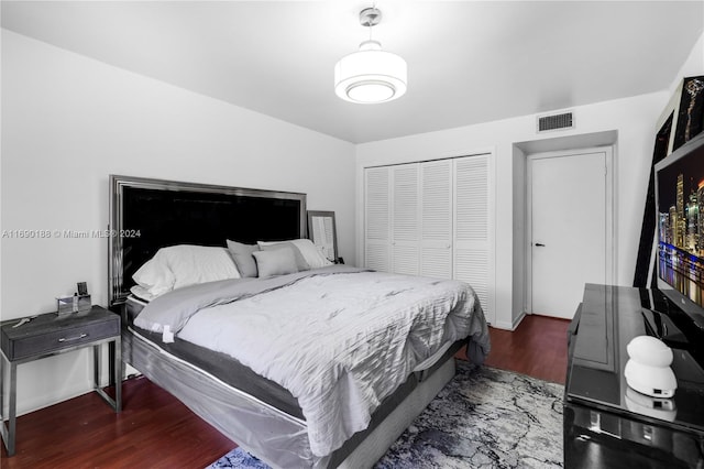 bedroom with dark wood-type flooring and a closet