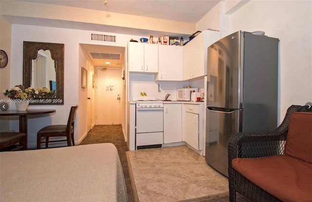 kitchen with white cabinets, stainless steel refrigerator, light colored carpet, and white range oven